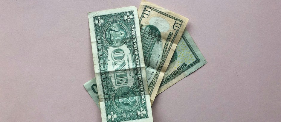 E-commerce winstgevendheid in 2025: Realistisch of illusie? Drie Amerikaanse dollarbiljetten op een roze achtergrond, illustratief voor online verdiensten